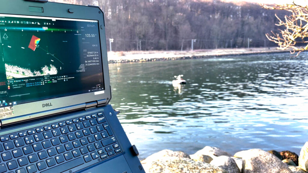 EIVA’s NaviSuite Kuda running on a laptop with an uncrewed surface vessel behind on a lake